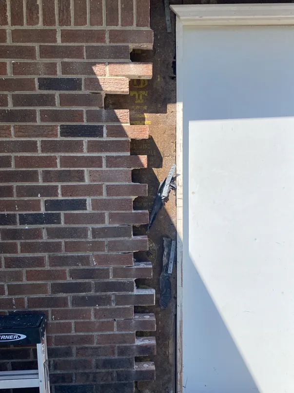 Brick removed beside a door during a wider-opening project
