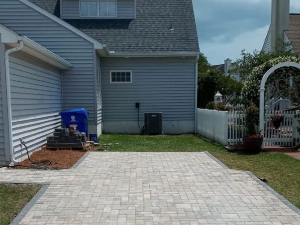 Finished light-colored paver driveway beside a home